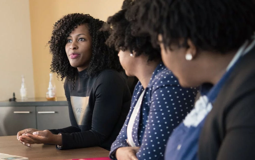 Women listening to another women at conference table