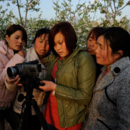 Photo of 2011-12 International Project Grantee Diedie Weng examining a camera with several young girls.