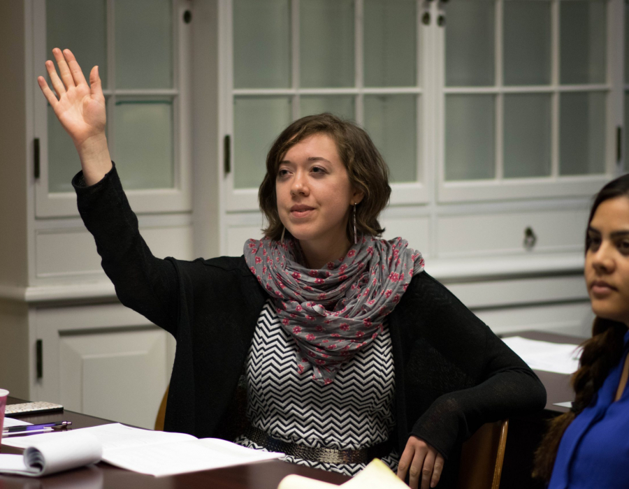 Young woman in salary negotiation training workshop raising her hand to ask a question.