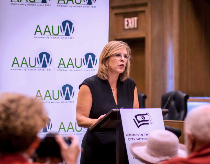 AAUW CEO Kim Churches stands at a podium speaking at press conference.