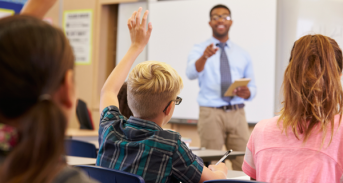 Students raise their hands in classroom