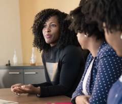 Women listening to another women at conference table