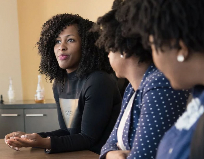 Women listening to another women at conference table