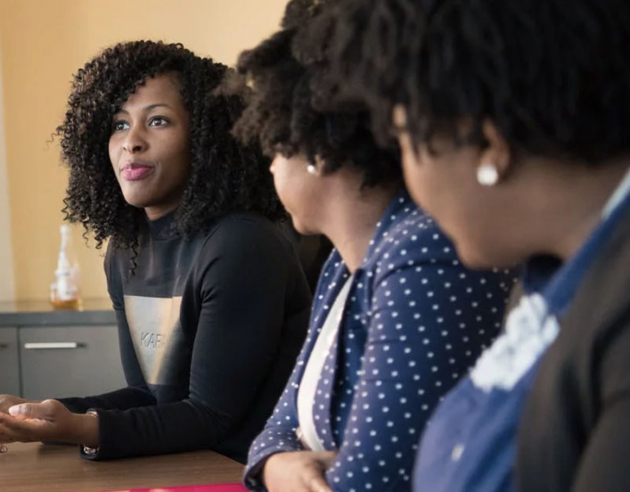 Women listening to another women at conference table