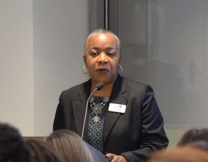 AAUW SVP Gloria Blackwell speaking at a podium in front of a crowd