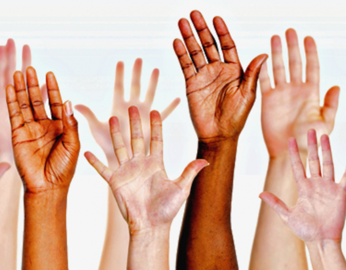 a group of raised hands in a vareity of skin hues