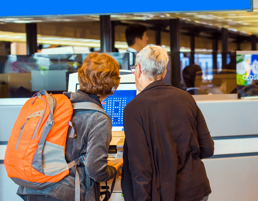 Two women check into their flight using an airport kiosk