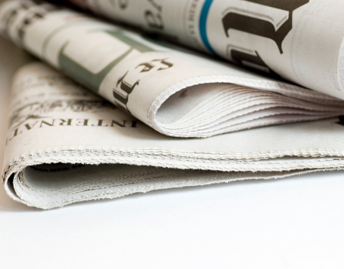 Newspapers folded and piled on top of each other.