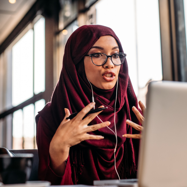 Businesswoman in hijab having a video chat on laptop while sitting at coffee shop.