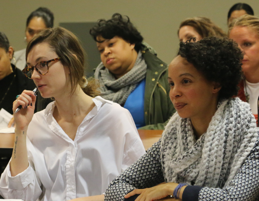 Two rows of female students attending a workshop in Washington DC. They are taking watching the presenter and taking notes.