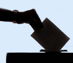 hand holding a ballot being entered in a ballot box