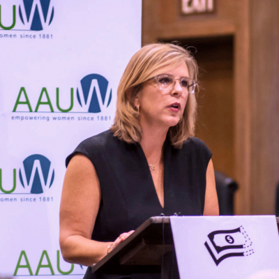 AAUW CEO Kim Churches stands at a podium speaking at press conference.
