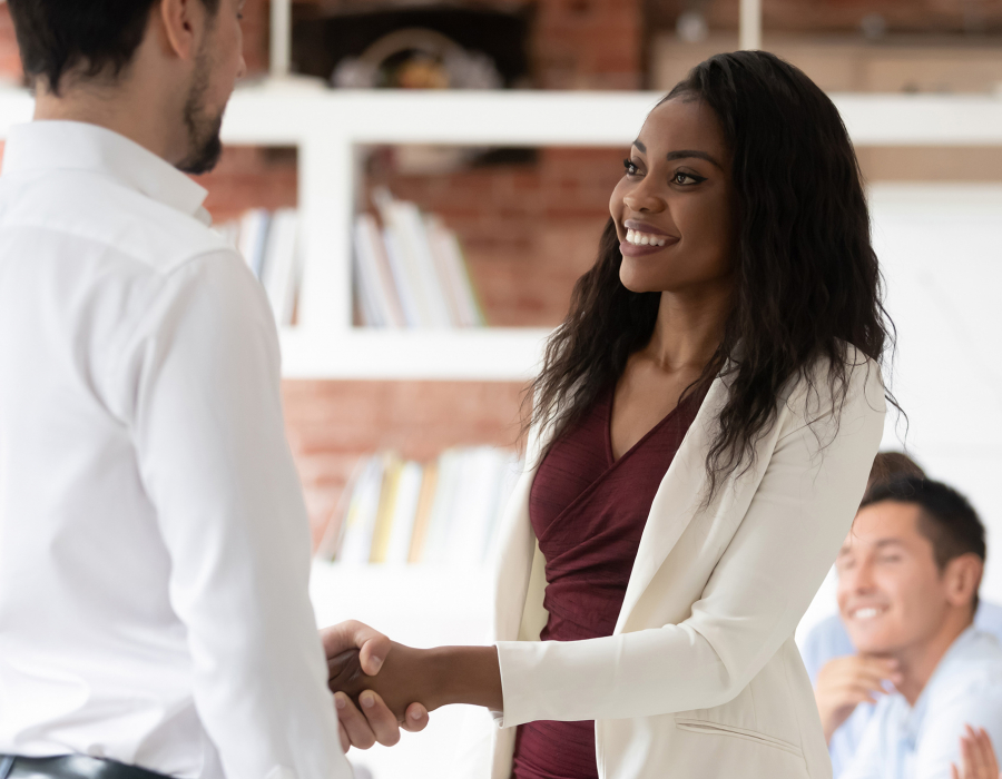 Young professional woman shakes hands with man, accepting job offer.