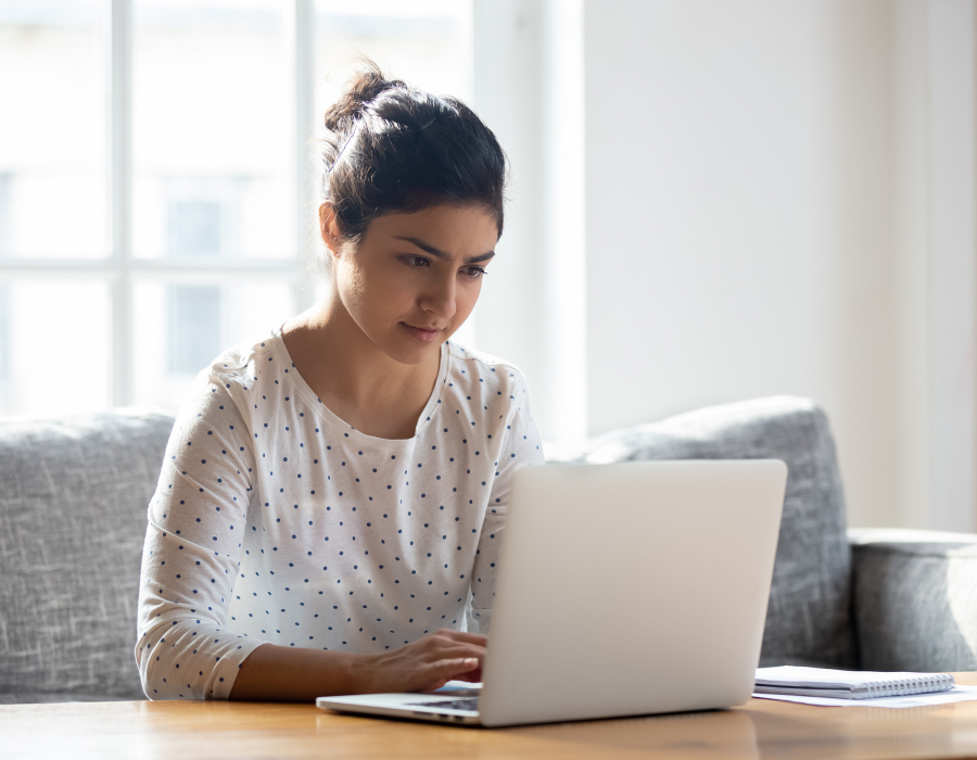 Focused young woman using laptop at home.