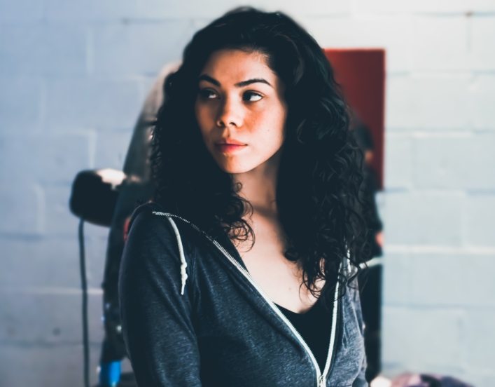 A Native American woman in a hoodie and black top. Photo courtesy of Obi Onyeador for Unsplash.
