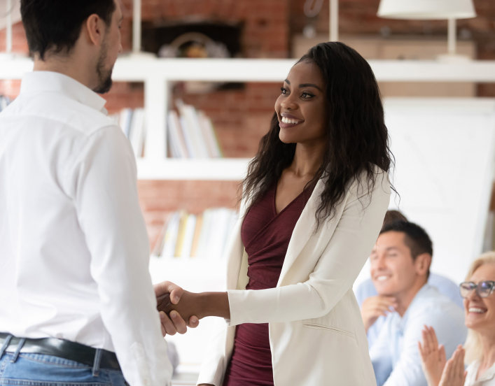 Young professional woman shakes hands with man, accepting job offer.