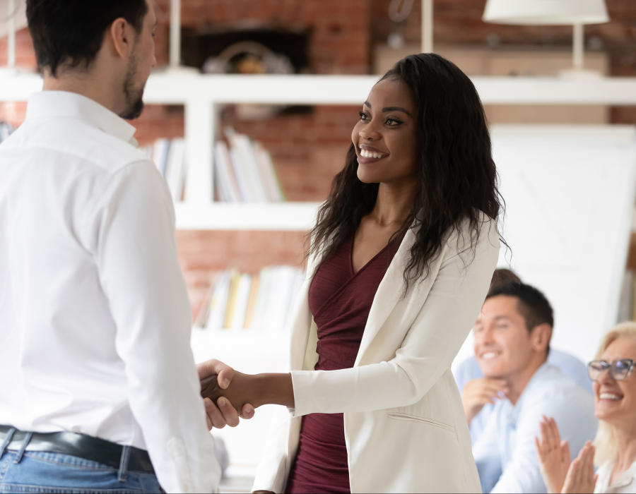 Young professional woman shakes hands with man, accepting job offer.