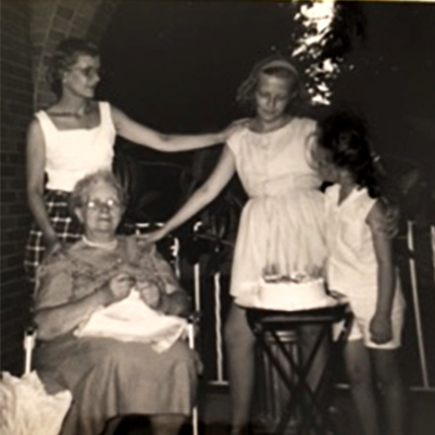 Old black and white photo of a young Janine with her sister, mother, and grandmother.