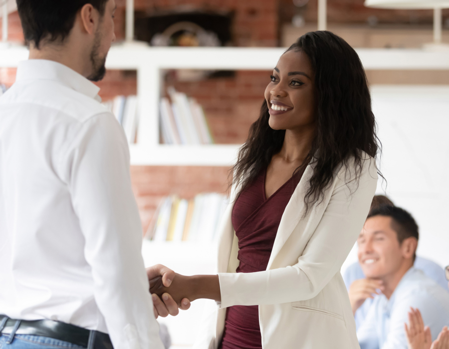 Young professional woman shakes hands with man, accepting job offer.