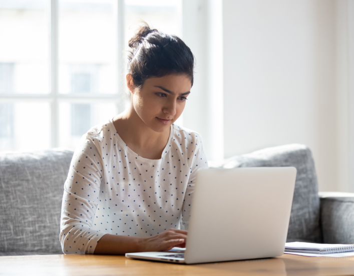 Focused young woman using laptop at home.