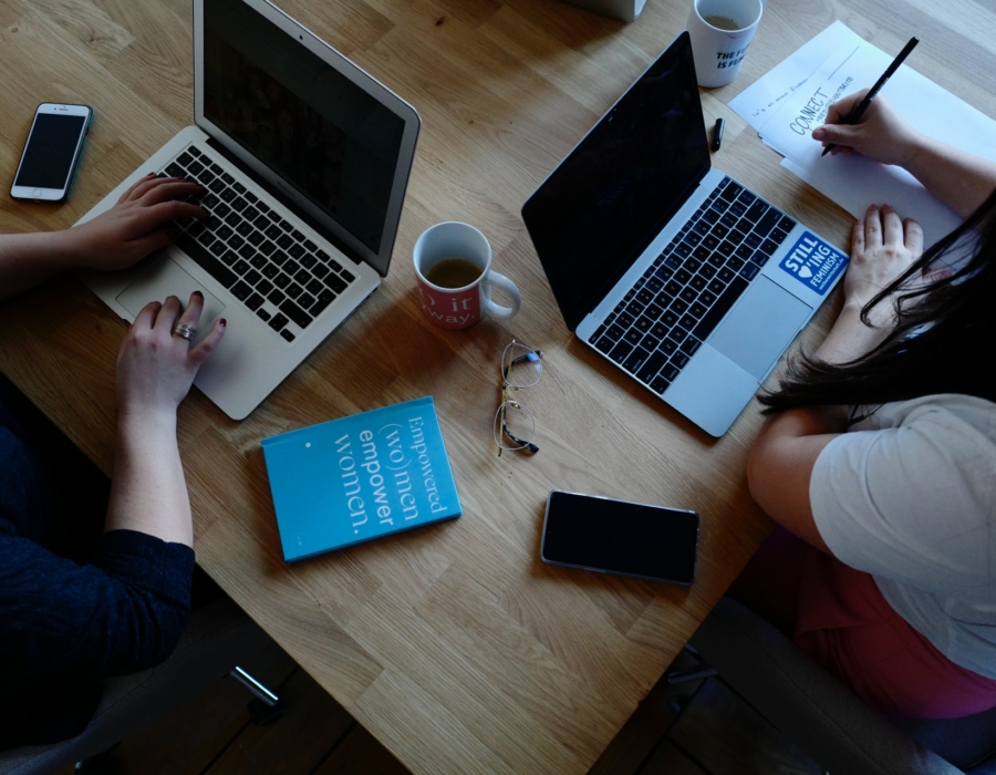 Photo from above of two young women on laptops.