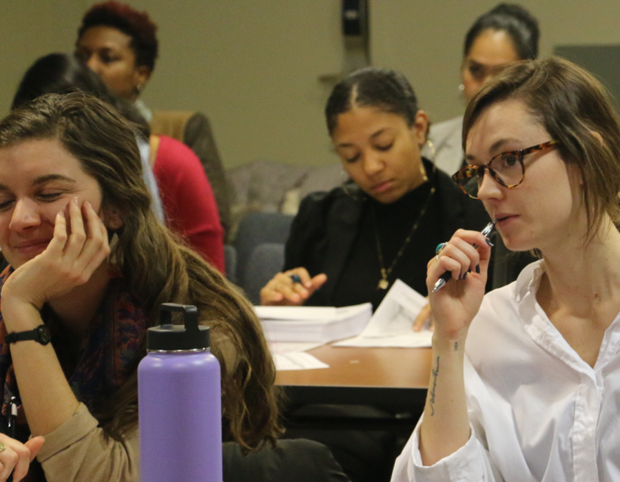 Two rows of female students attending a workshop in Washington DC. They are taking watching the presenter and taking notes.