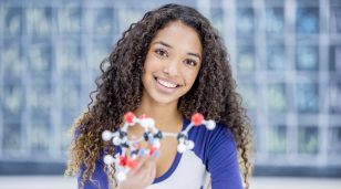 Smiling high school girl holding a model to illustrate STEM fields