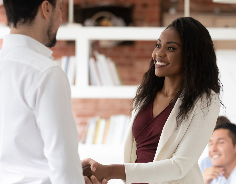 Young professional woman shakes hands with man, accepting job offer.