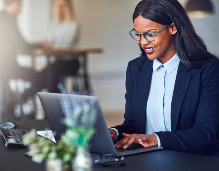 Smiling black woman in a suit on a laptop at a desk