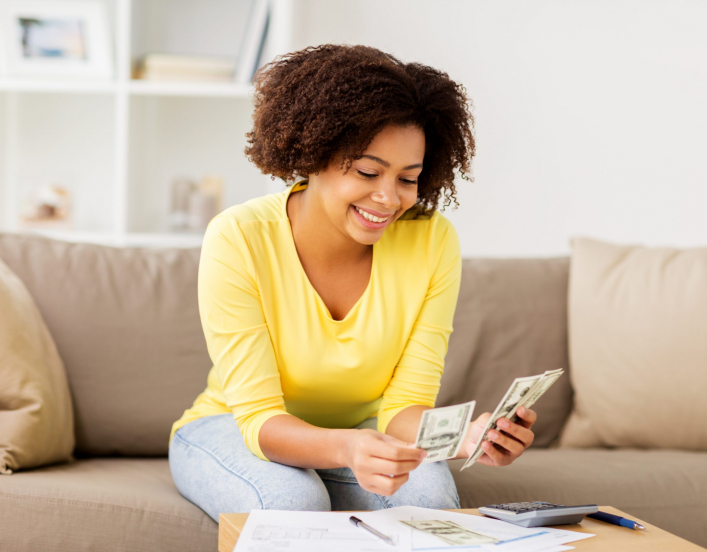 Woman sitting on sofa looking at spreadsheet and calculator