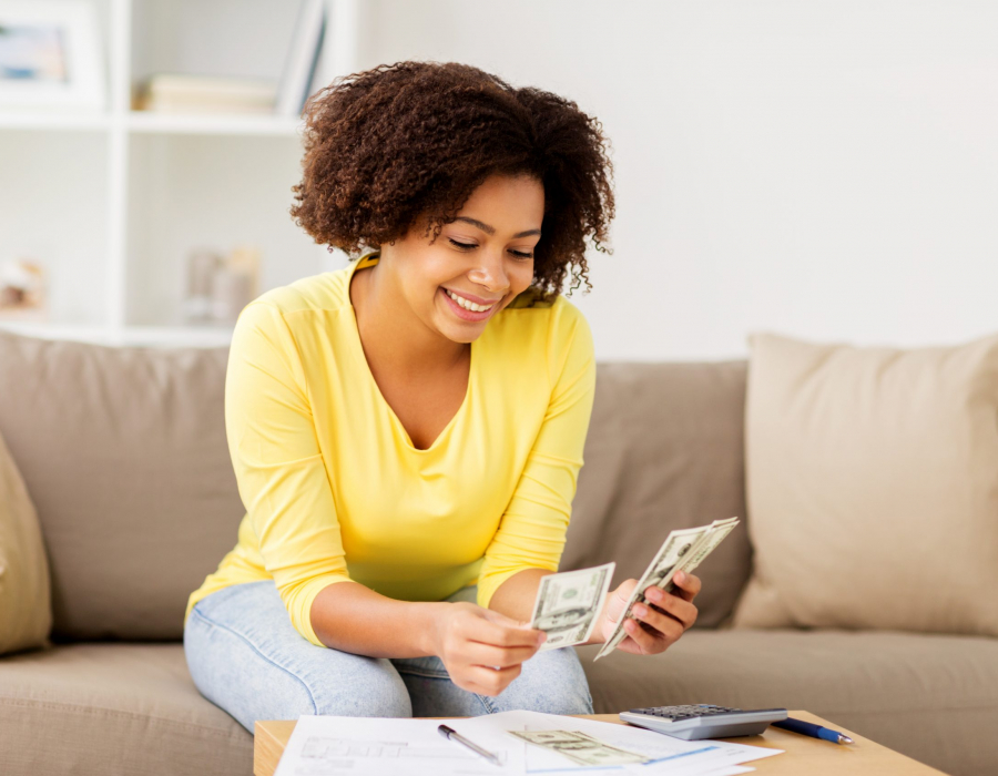 Woman sitting on sofa looking at spreadsheet and calculator