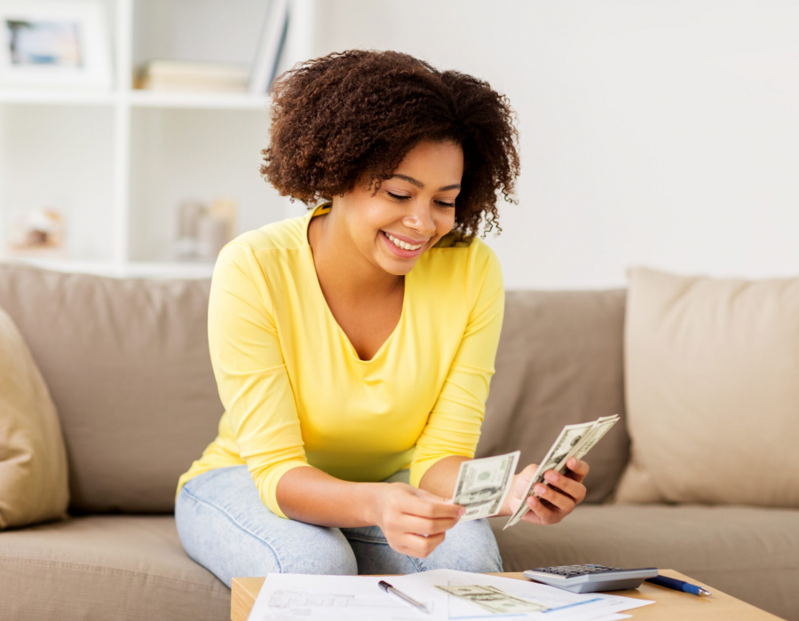 Woman sitting on sofa looking at spreadsheet and calculator