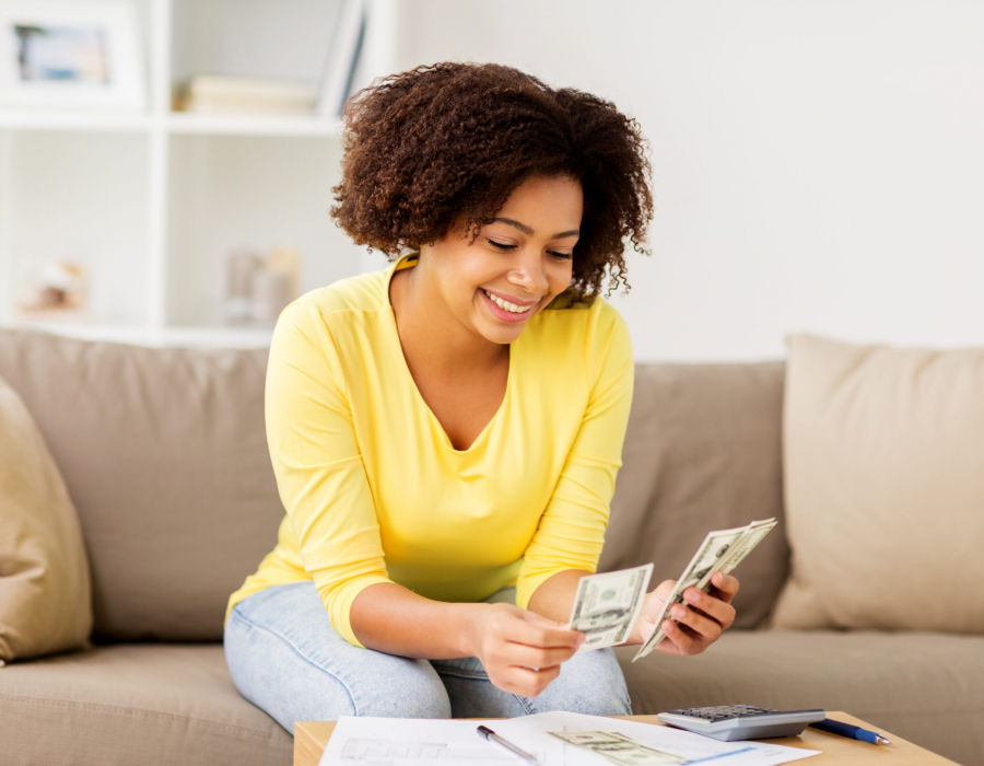 Woman sitting on sofa looking at spreadsheet and calculator