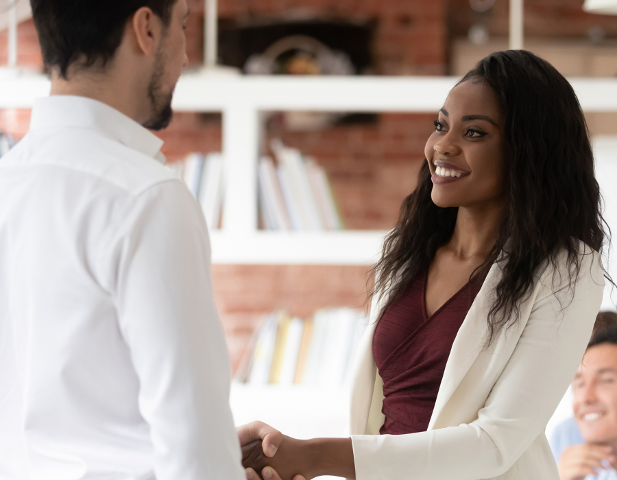 Young professional woman shakes hands with man, accepting job offer.