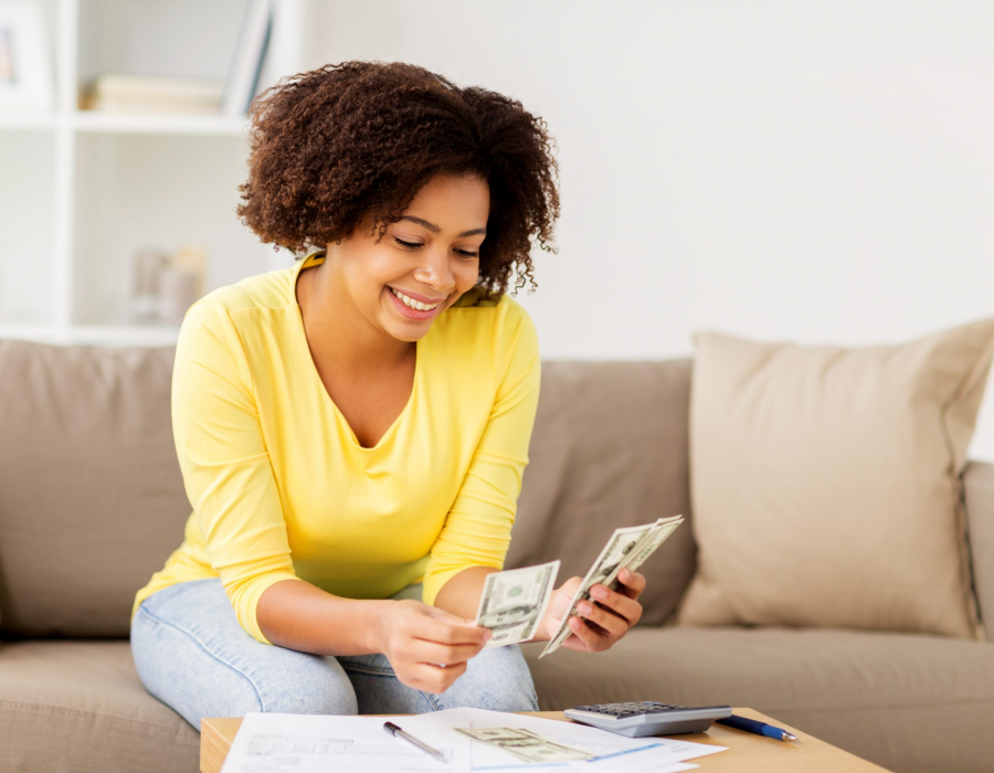 Woman sitting on sofa looking at spreadsheet and calculator