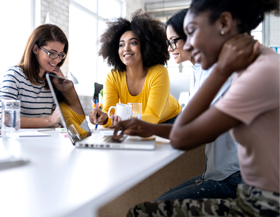 Several women sitting around a table working on a project together.