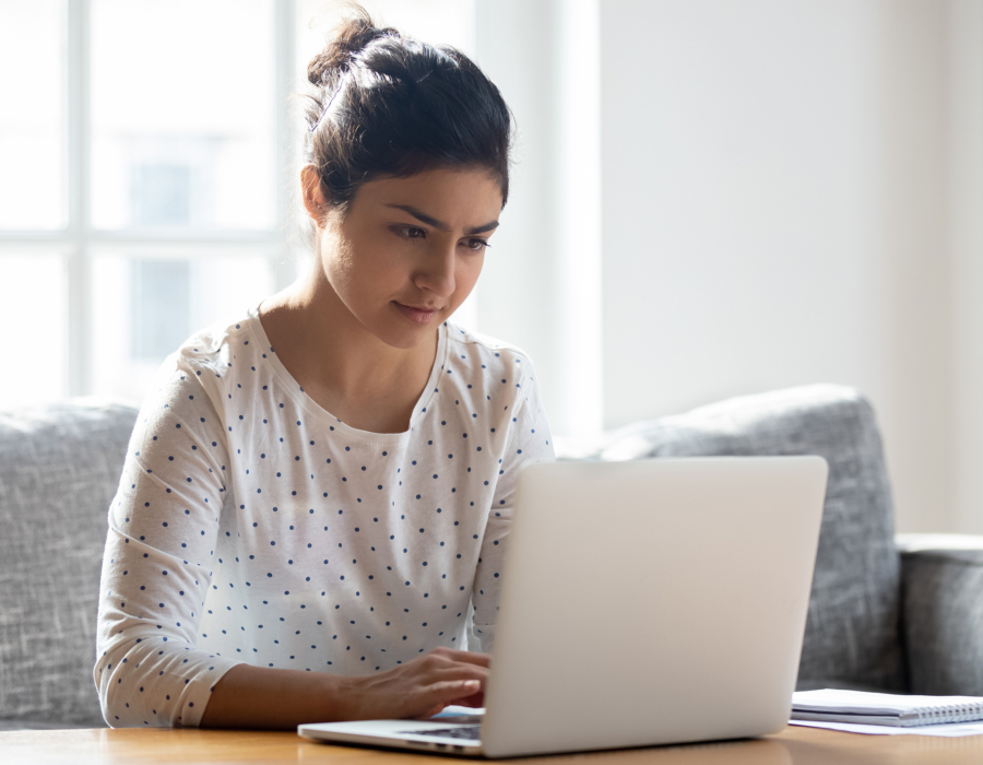 Focused young woman using laptop at home.