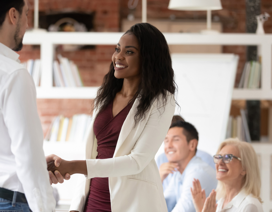 Young professional woman shakes hands with man, accepting job offer.