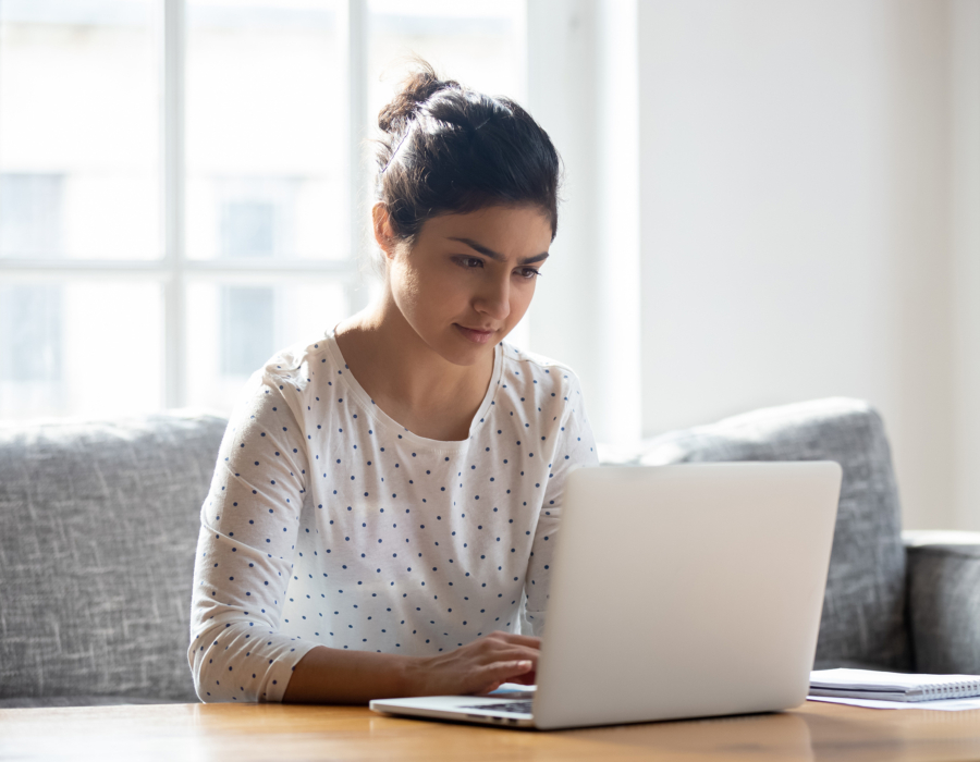 Focused young woman using laptop at home.