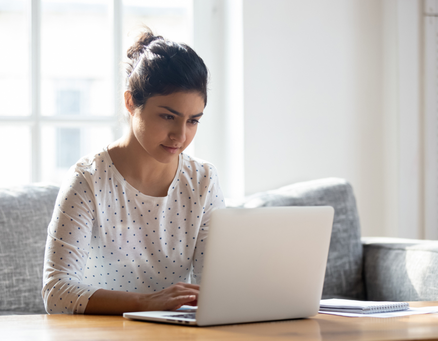 Focused young woman using laptop at home.