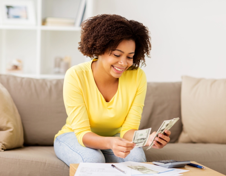 Woman sitting on sofa looking at spreadsheet and calculator